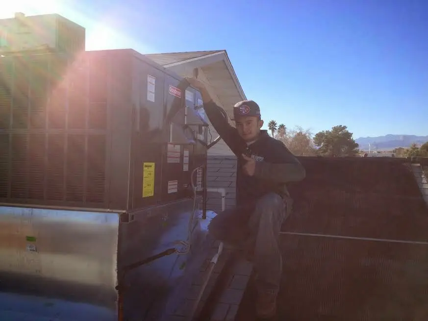 HVAC technician performing AC Tune-Up on a rooftop unit in Lubbock